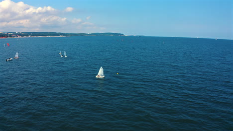 aerial view of optimist dinghy boats sailing on the blue waters of baltic sea in sopot, poland at sunny vacation day