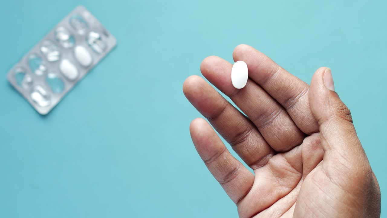Close-up of a hand holding a white pill