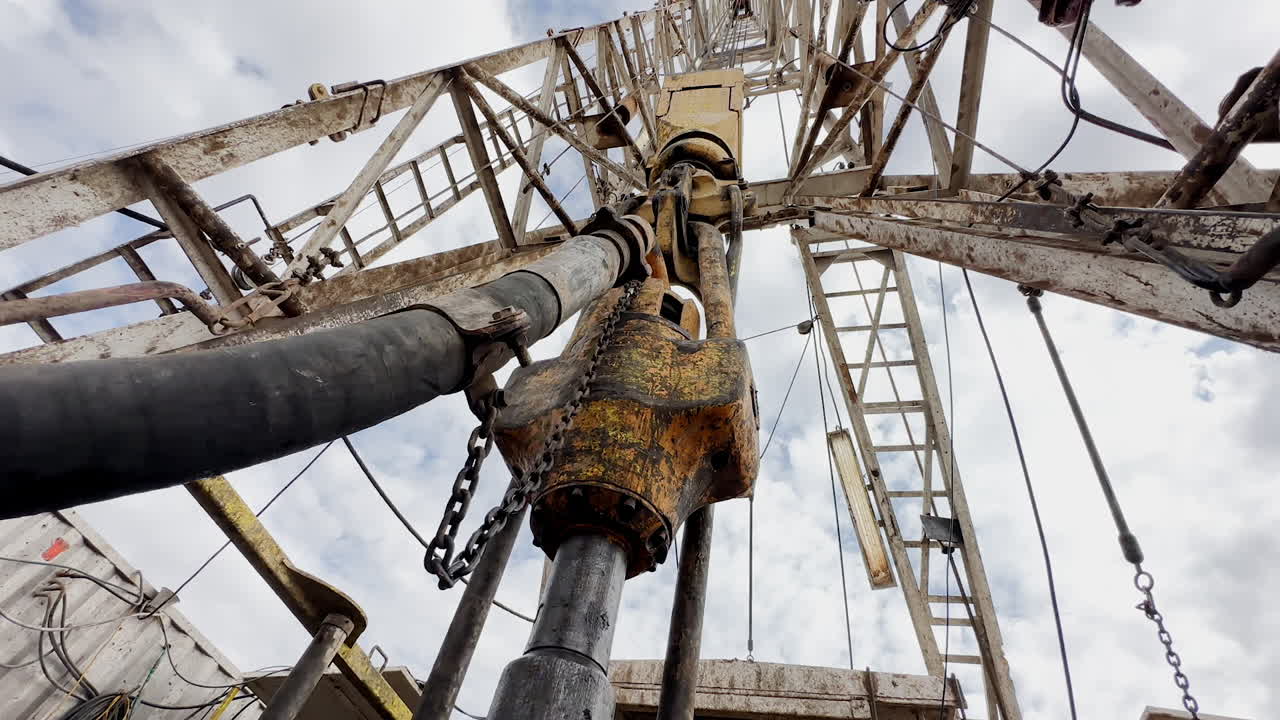 Quickly rotating boer drilling natural resources. Low angle view at the equipment producing oil or gas.
