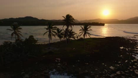 Vista-Aérea-De-La-Puesta-De-Sol-Dorada-Con-Palmeras-Tropicales-En-La-Playa-De-El-Cayito,-República-Dominicana