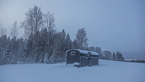 Static-shot-of-wooden-cabin-surrounded-by-white-snow-in-winter-landscape-at-daytime-in-timelapse