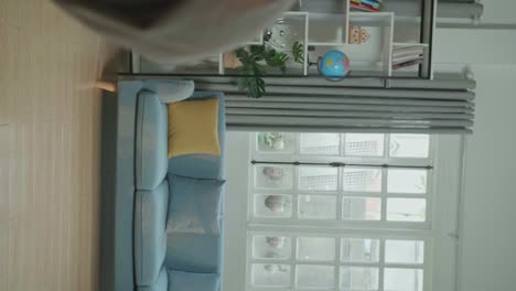 full body of asian man shows trick with disappearing while recording video content for social networks in cozy room