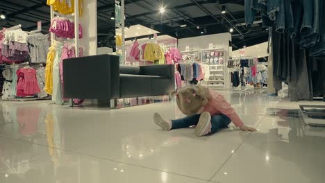 little child in clothing store sits on the floor and laughs slow motion