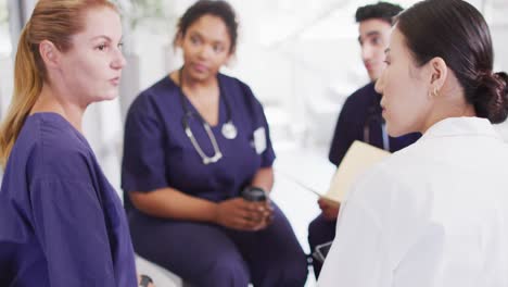 Video-of-caucasian-female-doctor-talking-with-diverse-medical-colleagues-in-hospital-meeting