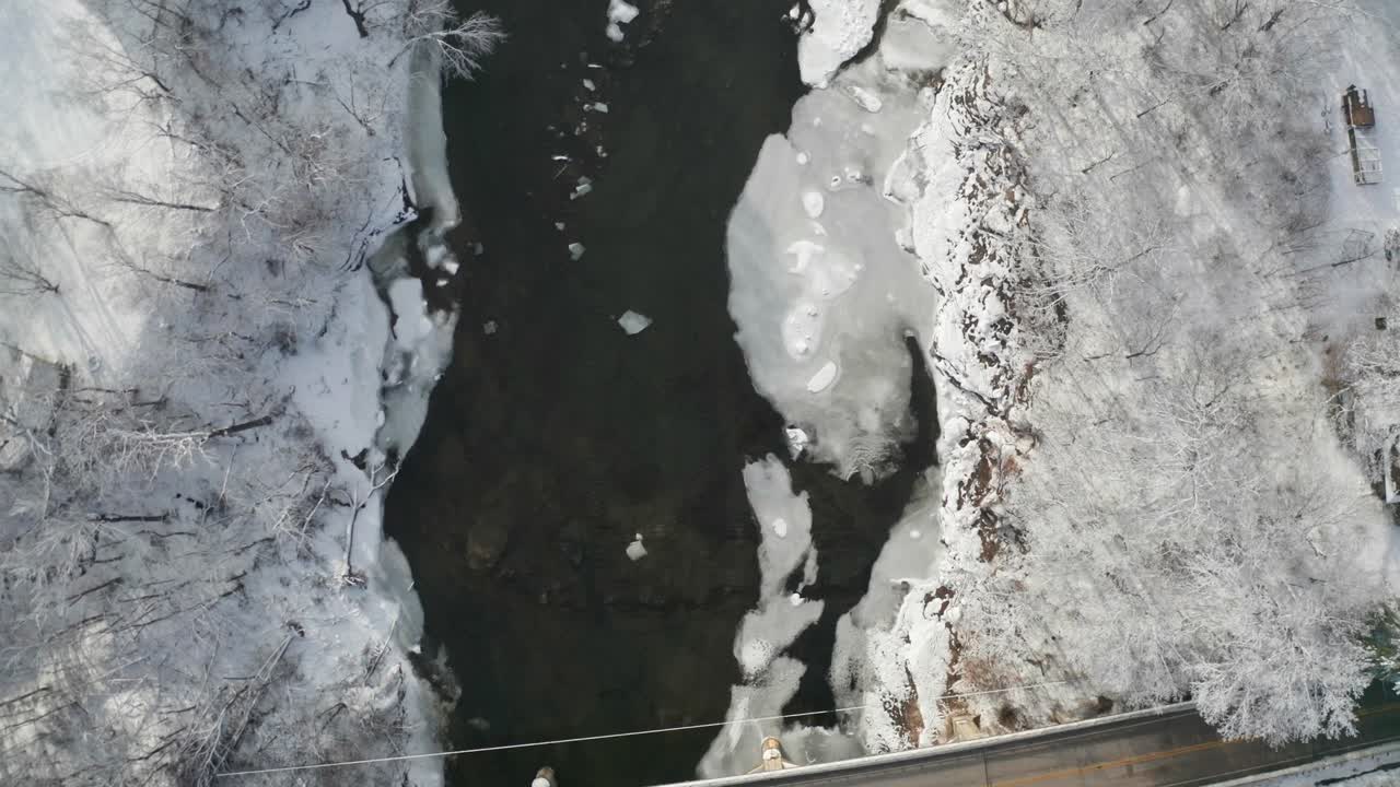 Top-down view of frosty winter river and two-lane bridge