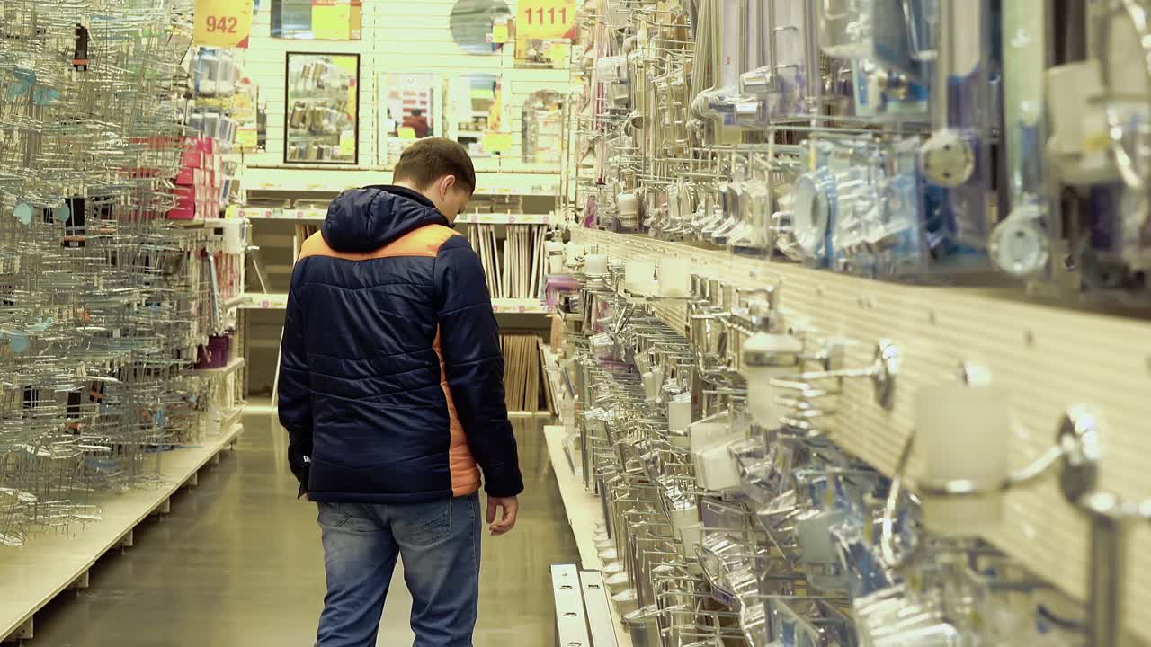 un joven está considerando accesorios de baño en una tienda de materiales de construcción