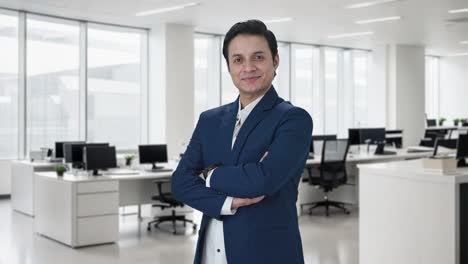 retrato de un feliz hombre de negocios indio de pie con las manos cruzadas