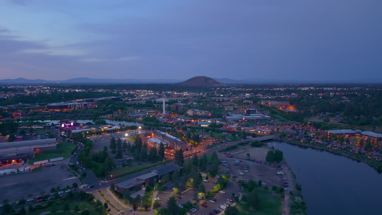 Aerial drone view of the old mill district in Bend Oregon. Drone flying backwards over Deschutes River at night. Pilot Butte in the distance