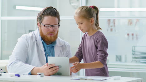 doctor and little girl using tablet in medical office