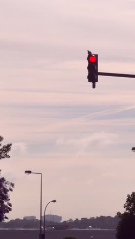 airplane in cloudy sky near red traffic light