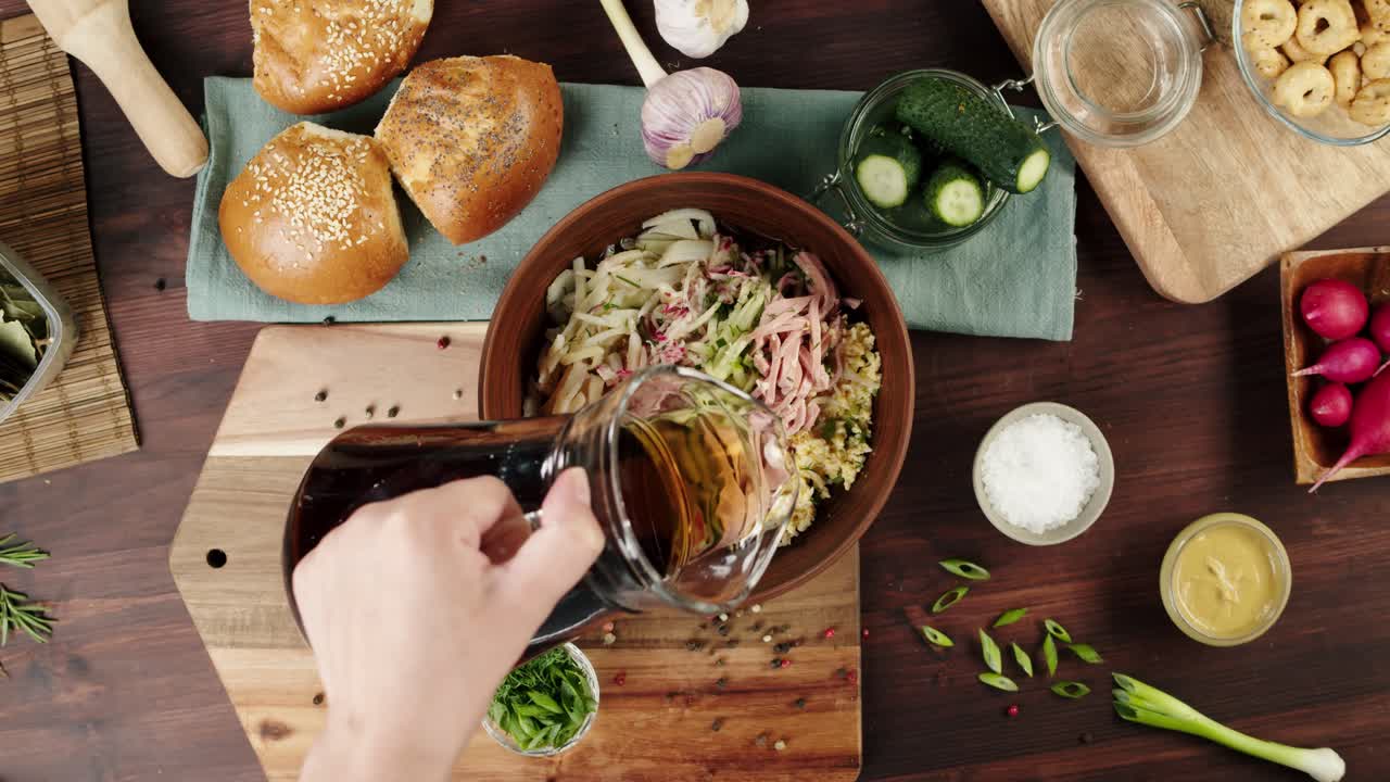 Persona virtiendo Kvass en ingredientes frescos para ensalada Okroshka