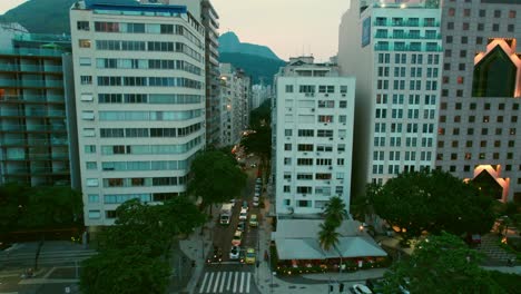 aerial drone pan left above copacabana neighborhood, dusk, rio de janeiro brazil resorts and beachfront hotels, main avenue