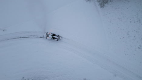 Top-down-aerial-of-Tractor-maintaining-road-clean-from-snow-after-blizzard