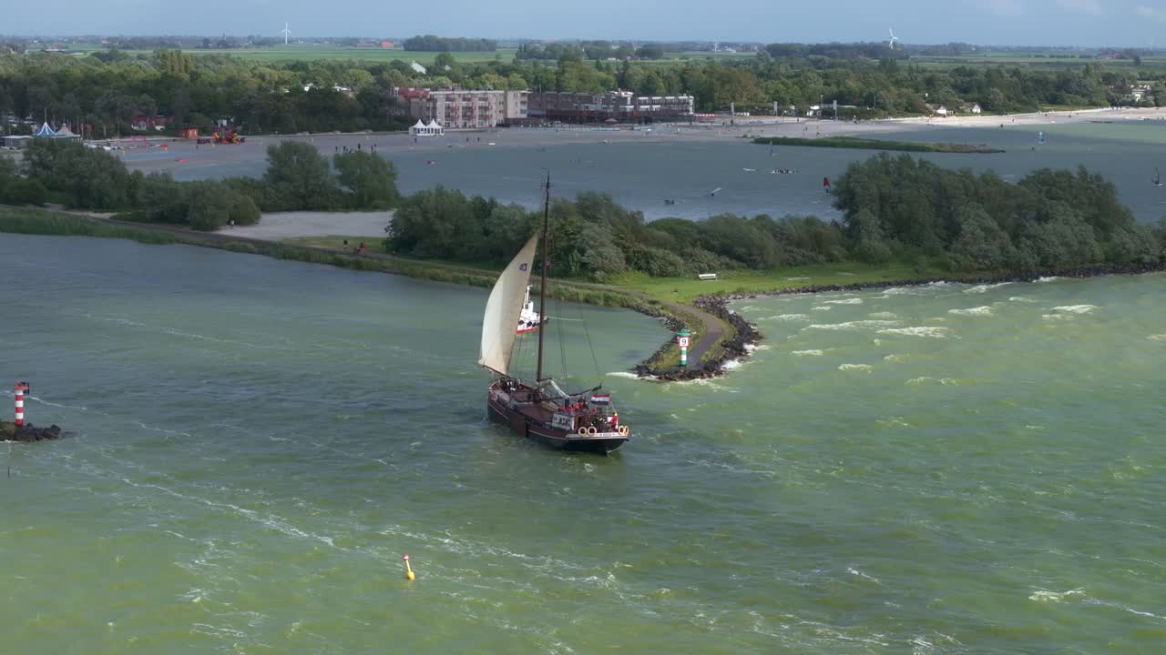 Letecký pohled na Makkum s IJsselmeerem, větrem, plachtěním, zobrazující zlatou pobřežní scenérii v Nizozemsku