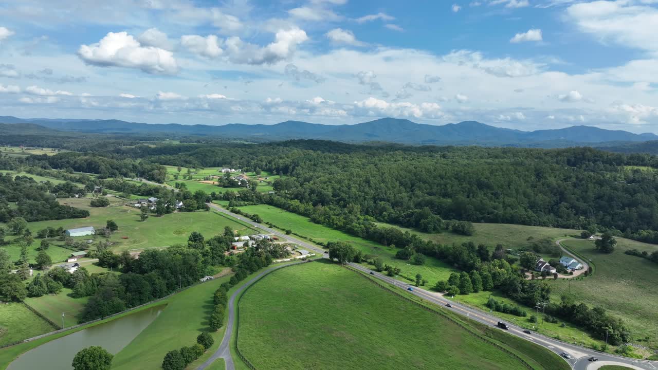 Driving cars on rural interstate road of American suburb. Sunny summer day between blue ridge mountains in Virginia. Suburb neighborhood and farmsteads in idyllic district of town