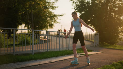 joven patinando al aire libre a lo largo de un camino alineado con barandillas de hierro, manteniendo el equilibrio mientras se mueve bajo el resplandor del atardecer, con el paisaje urbano visible en el fondo borroso y otras personas en la distancia