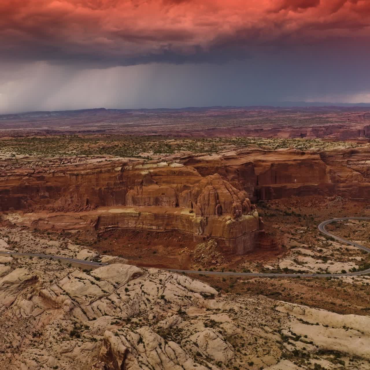 Amazing dramatic blue and pink cloudscape over the majestic canyon in Utah, USA. Wavy highway with cars moving on running near the rocks