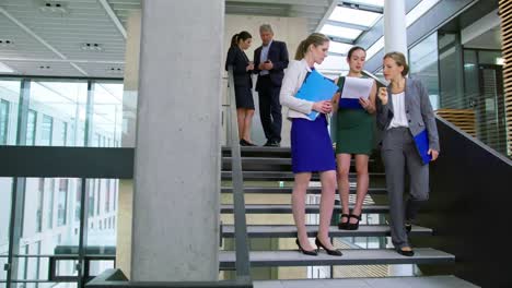 Businesswomen-discussing-on-document-while-standing-on-stairs