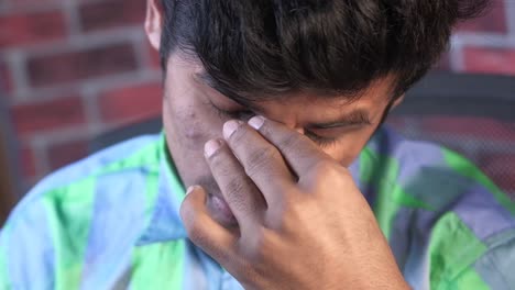 sad young man rubbing his eyes