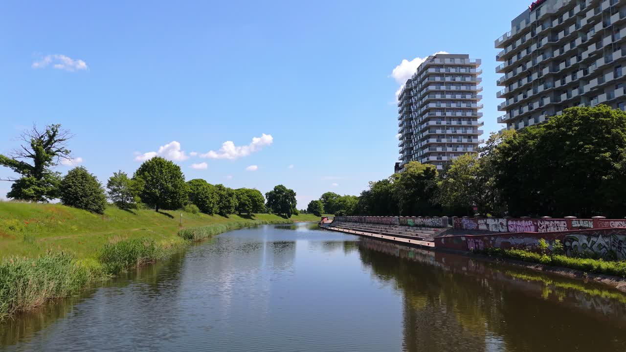 Modern riverside apartment blocks, trees, and water in Wroclaw, Poland, showing the mix of urban living, green areas, and contemporary architecture, aerial view