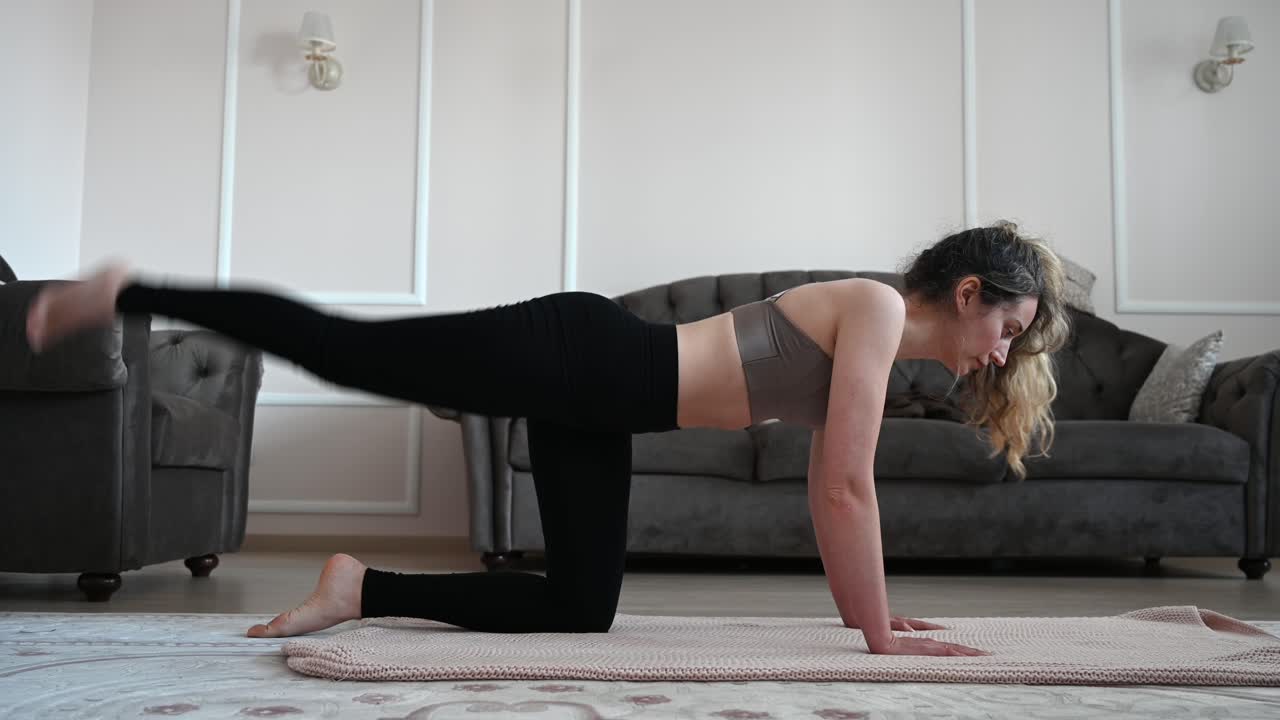 A woman exercising indoors, performing leg lifts on a yoga mat in a cozy living room