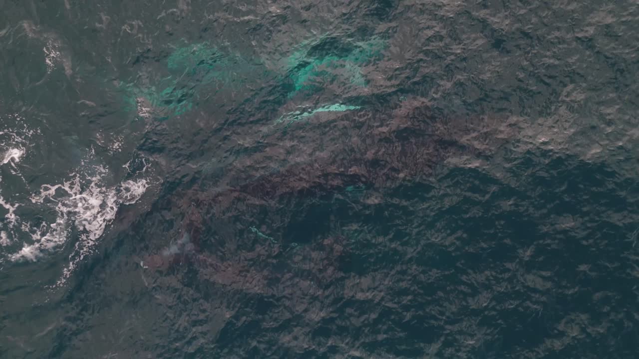 Breathtaking aerial footage of a humpback whale and calf gliding through the ocean, surfacing for air with mesmerizing water reflections