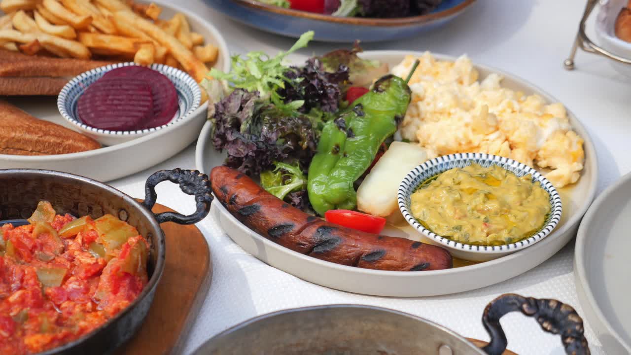 A delicious breakfast with scrambled eggs, sausage, salad, and fries