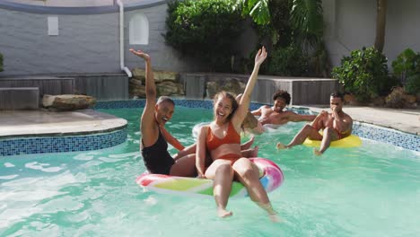 happy diverse male and female friends having fun and laughing in swimming pool