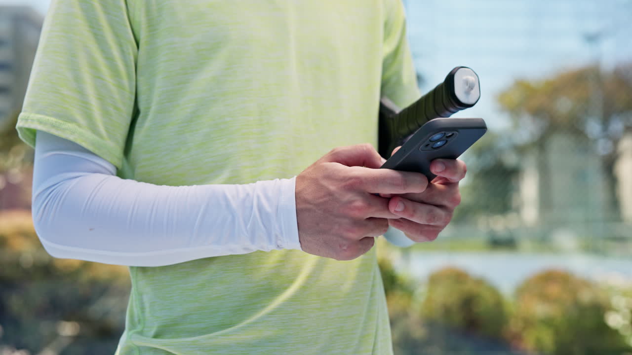 Uomo che usa lo smartphone e tiene una racchetta da tennis all'aperto