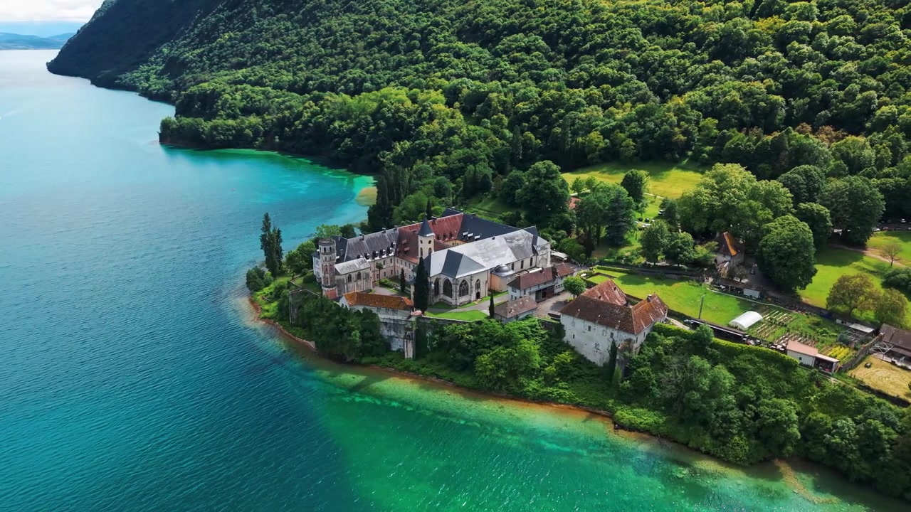Letecký záběr nad opatstvím Hautecombe, které se nachází na břehu jezera Lac du Bourget poblíž Aix-les-Bains za slunečného dne, departement Savojsko, region Auvergne-Rhône-Alpes, Francie.