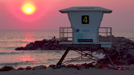 a sunset behind a lifeguard station along a california beach