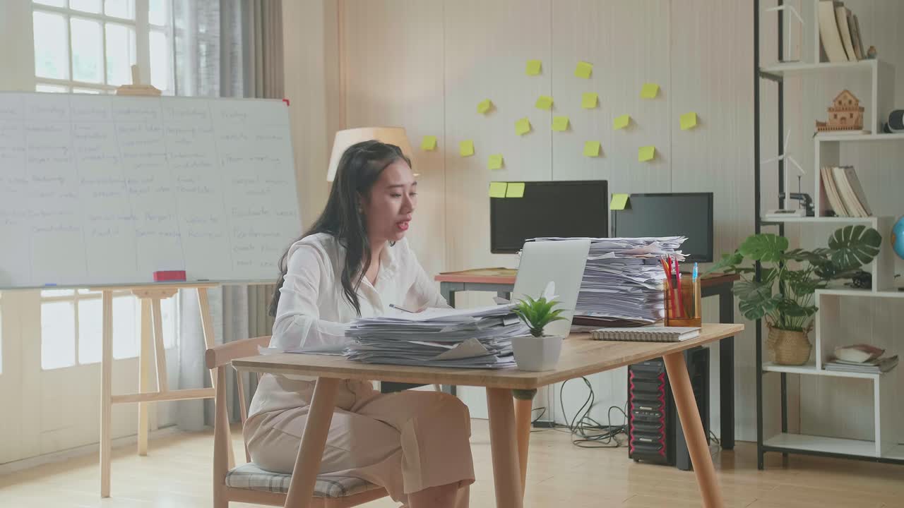 사무실에서 노트북으로 비디오 통화를 하는 동안 종이에서 일을 설명하는 문서를 가진 아시아 여성