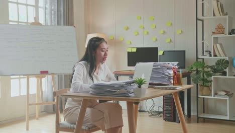 mujer asiática con documentos que explican el trabajo en papel mientras tiene una llamada de video en una computadora portátil en la oficina