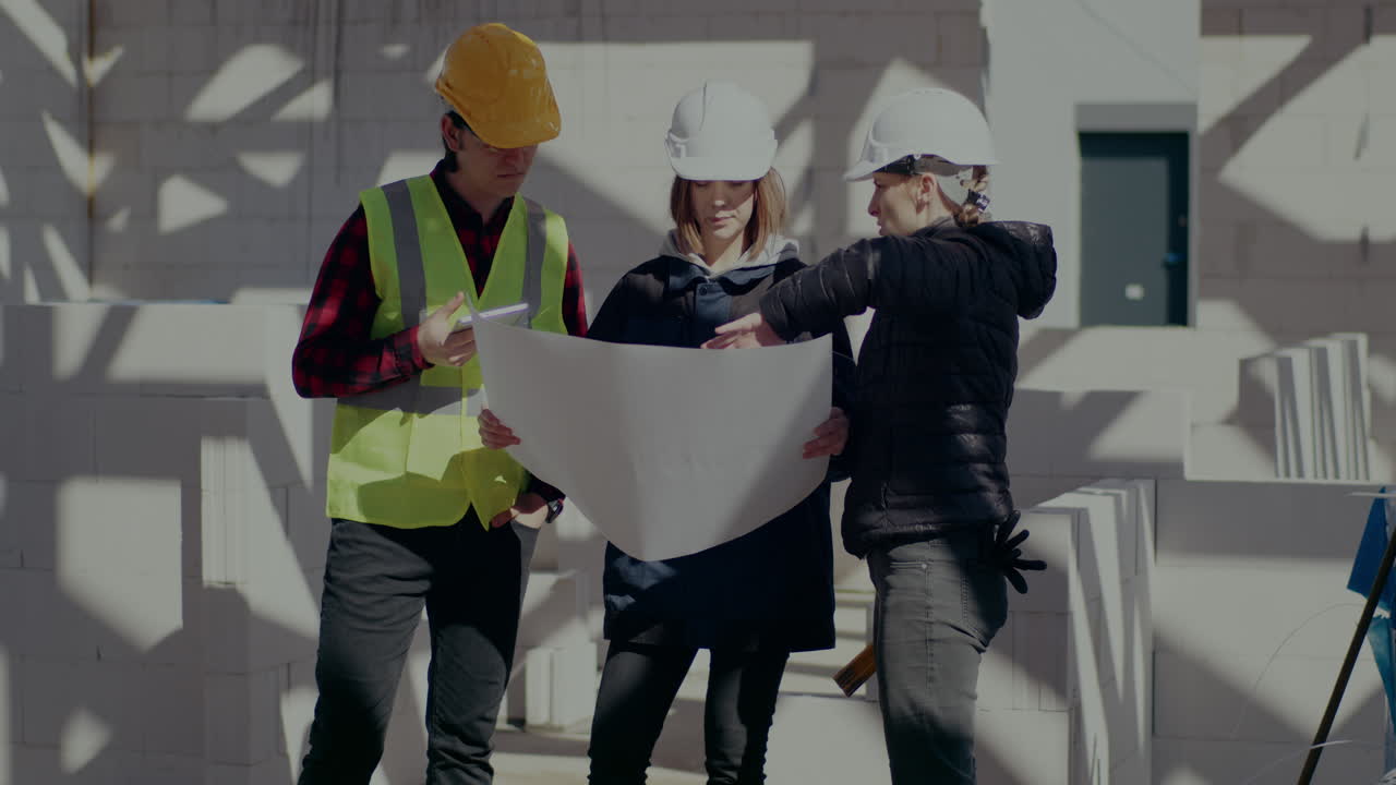 Confident female engineer and architect discussing over blueprint by contractor standing together at construction site