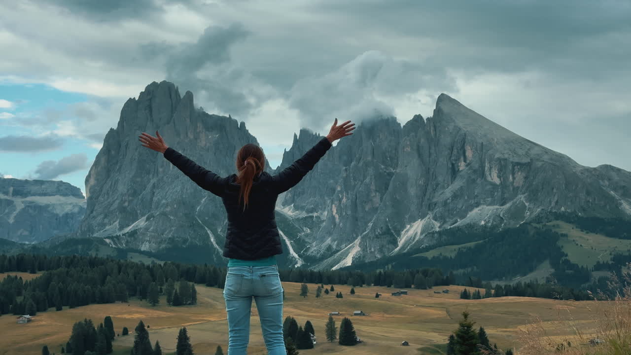 Slow motion video of a woman opening her arms to the majestic mountains of Alpe di Suisi in the Dolomites