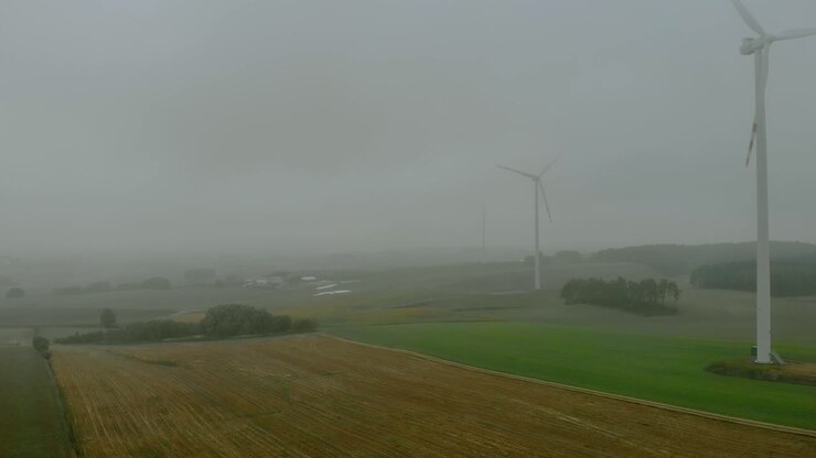 Riprese aeree ravvicinate di un parco eolico, mulino a vento durante la nebbia, paesaggio grigio intorno, energia rinnovabile in campo aperto, sotto paesaggio naturale, l'energia verde è importante