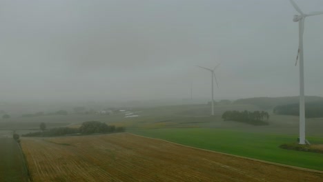 Aerial-footage-close-up-to-wind-farm,-windmill-during-fog,-grey-landscape-around,-renewable-energy-in-the-open-field,-below-natural-landscape,-green-energy-is-important