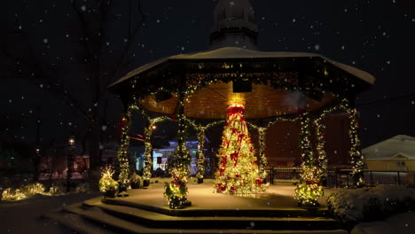 community park gazebo and decorated christmas tree at night during snowstorm