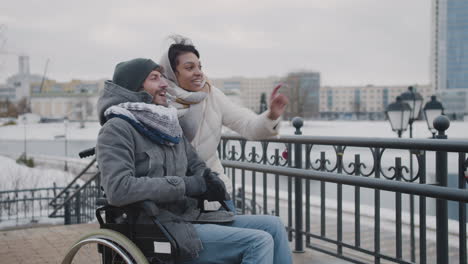 muslim woman and her disable friend looking at something in the distance in city in winter 3