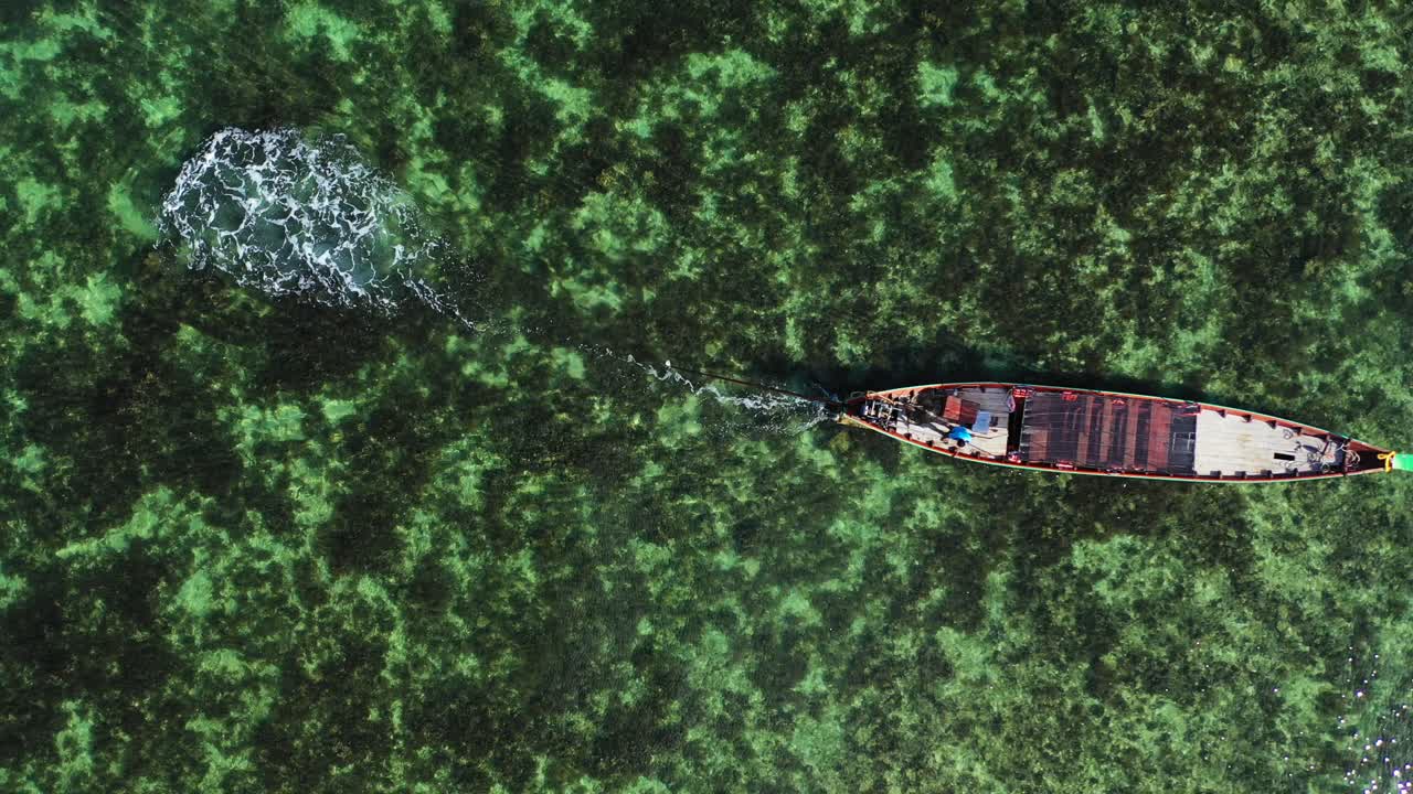 Long transportation boat sailing slowly across calm clear water of turquoise lagoon full of coral reefs on seabed in Philippines