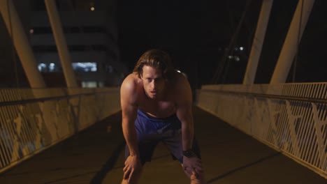 Hombre-Caucásico-Sin-Camisa-Haciendo-Deporte-En-Un-Puente-Por-La-Noche