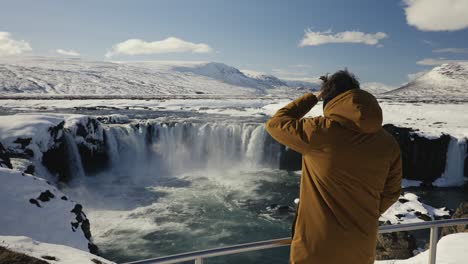 man come to metal safety barrier near godafoss waterfall sightseeing area