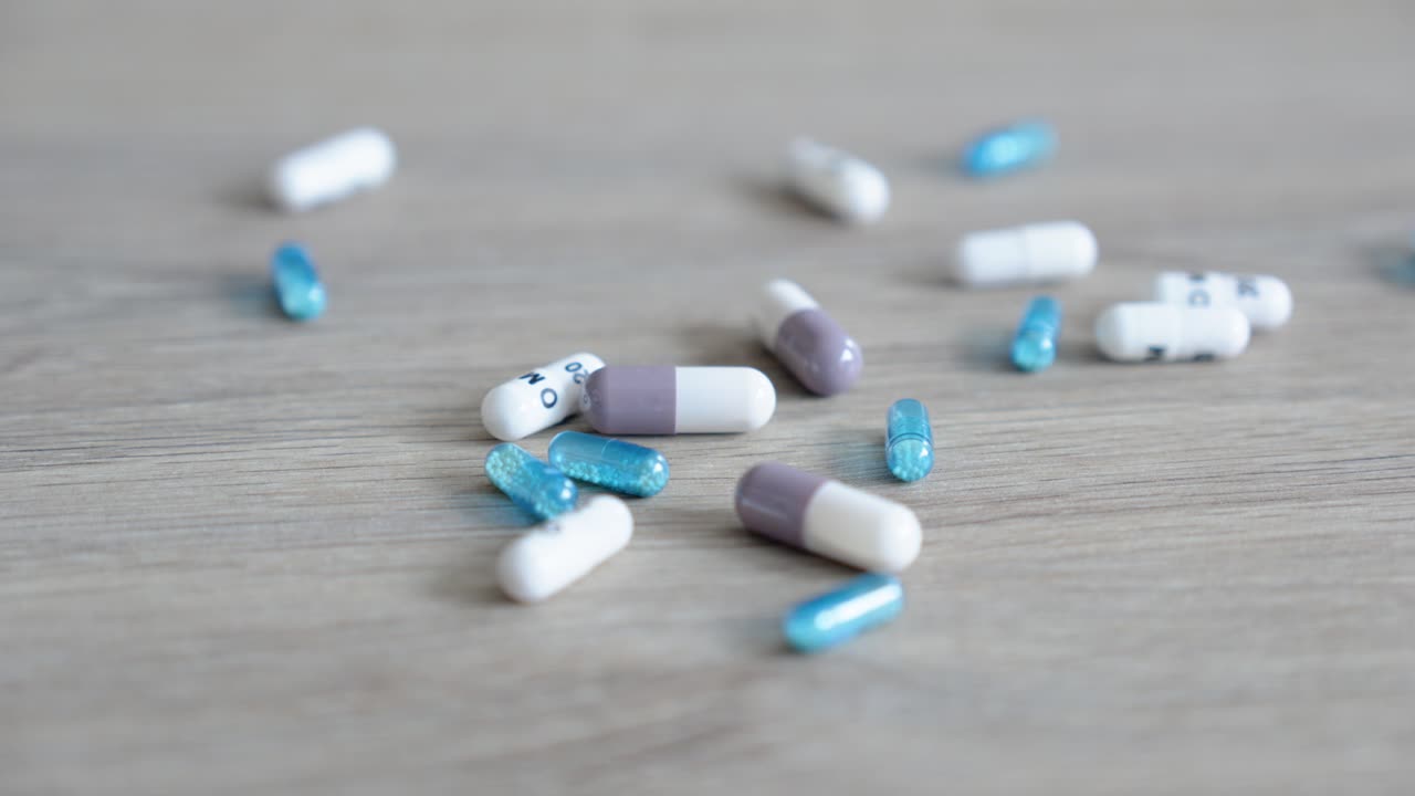 close-up light on a wooden table with various capsules falling on it