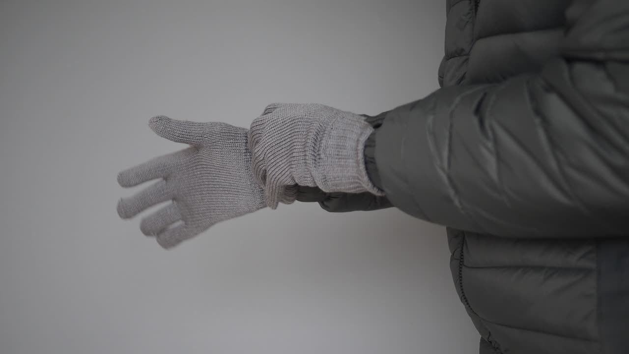 Person tager en grå strikhandske på