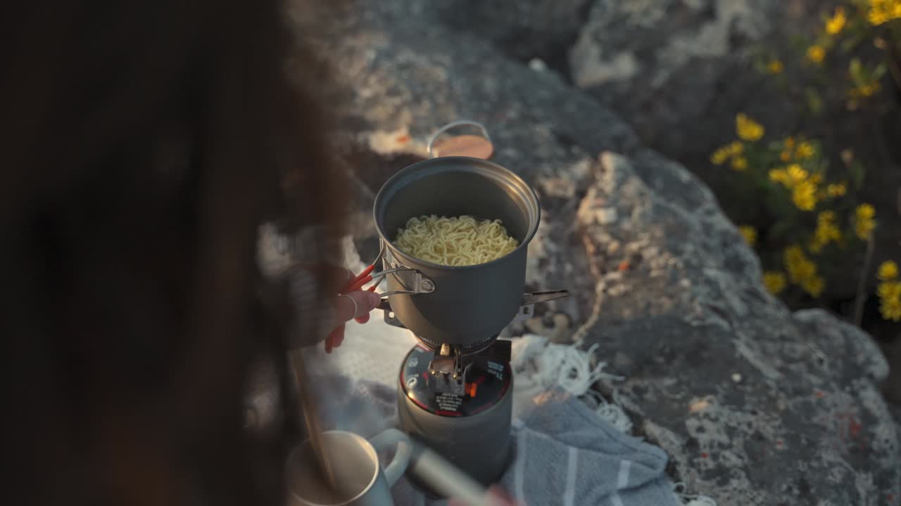 Woman Cooking Ramen Noodles Outdoors at Sunrise