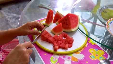 hands of woman cut vibrant delicious watermelon into small pieces