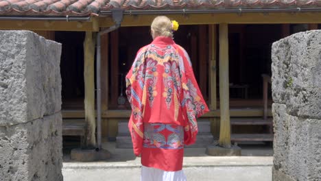 Frau-Bekommt-Ein-Traditionelles-Japanisches-Haus-In-Der-Okinawa-Welt-Naha-Japan-Und-Trägt-Ein-Ryusou-Kimono-Kleid.-Sommer-Heißer-Tag.-Holzhaus-Aus-Stein.-Zieht-Geta-Schuhe-Aus