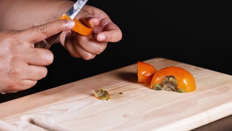 hands carefully slicing a ripe persimmon