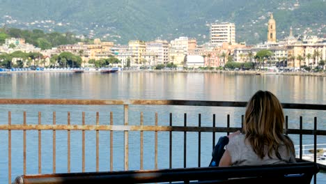 woman sit bench city sea bay skyline back view rapallo italian riviera italy