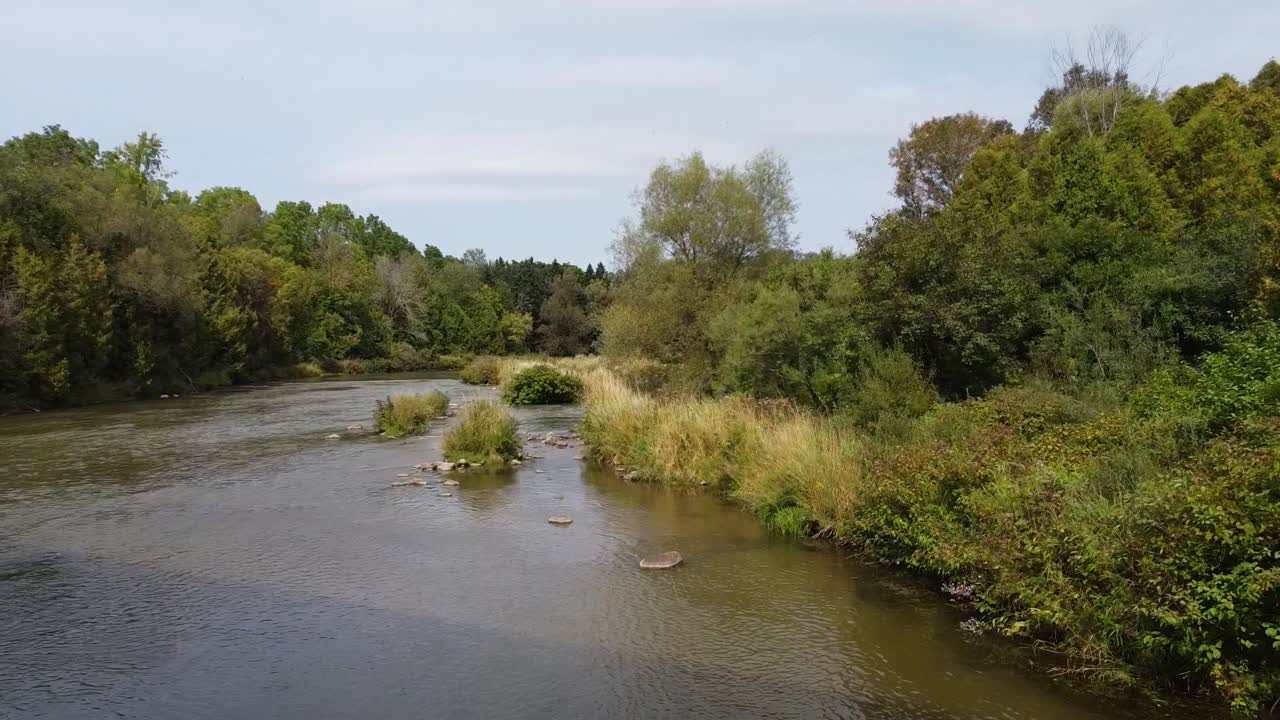 Baglæns droneoptagelse over den idylliske Ontario-flod under en bro i Canadas vildmark
